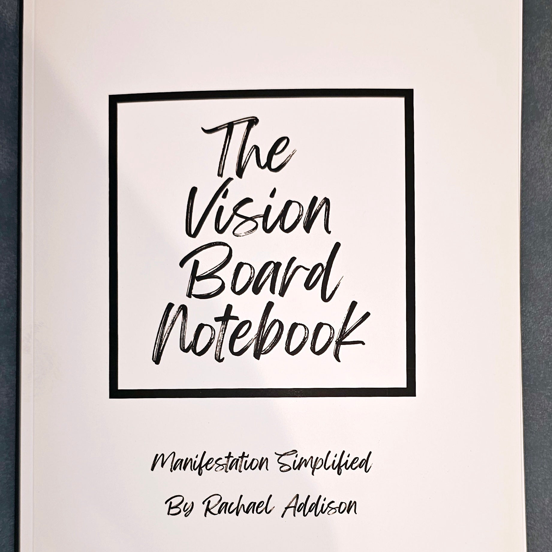 White notebook with black text The Vision Board Notebook: Manifestation Simplified. Wordkind.