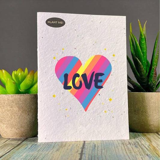 Seed paper greeting card with a striped heart (blue, yellow, pink, orange) and Love written in black. Wordkind.