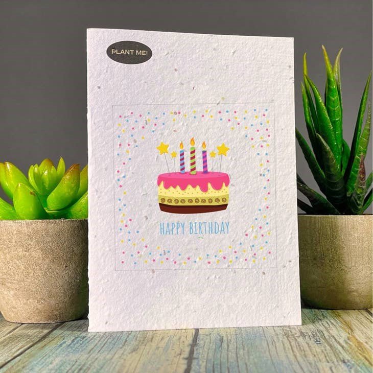Seed paper birthday card with pink and yelllow cake with candles, and happy birthday in blue text. Wordkind. 